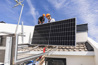 Ingenieure bei der Installation von Solarzellen auf dem Dach - JCCMF10055