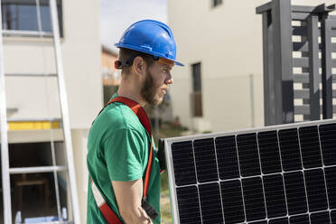 Techniker hält Solarmodul an einem sonnigen Tag - JCCMF10060