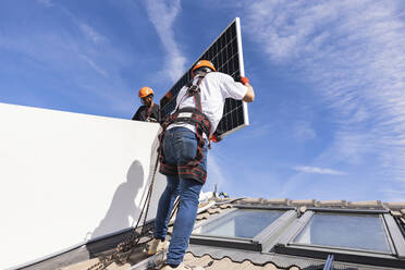 Ingenieure installieren Sonnenkollektoren unter dem Himmel - JCCMF10068