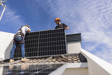 Ingenieure installieren gemeinsam Sonnenkollektoren auf dem Dach - JCCMF10077