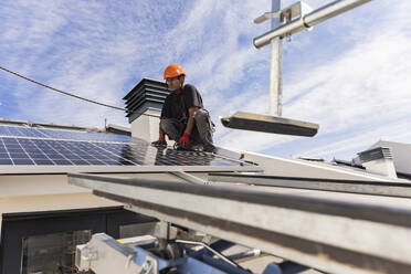 Ingenieur bei der Installation von Solarzellen unter bewölktem Himmel - JCCMF10087