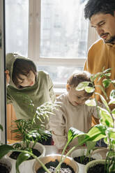 Father and sons standing near plants at home - ANAF01132