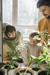 Vater und Söhne stehen in der Nähe von Pflanzen zu Hause - ANAF01132