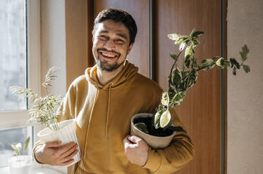 Glücklicher Mann mit Topfpflanzen zu Hause - ANAF01136