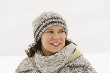Nachdenklich lächelnde Frau mit Strickmütze im Winter - SEAF01836