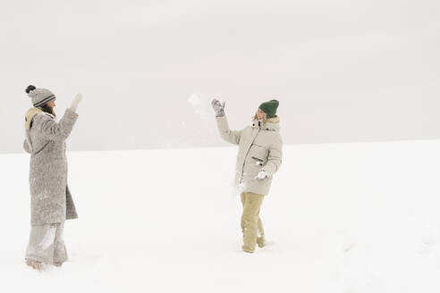 Glückliche Freunde spielen mit Schneeball im Winter - SEAF01837