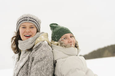 Glückliche Freunde mit Strickmützen, die sich im Schnee vergnügen - SEAF01841