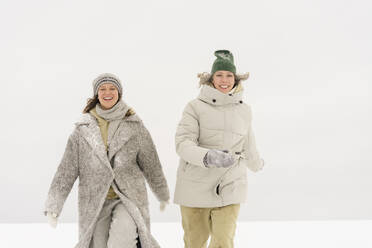 Happy woman walking with friend in winter - SEAF01843