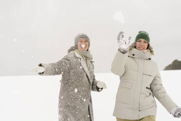 Glückliche Frauen beim Schneeballwerfen im Winter - SEAF01847