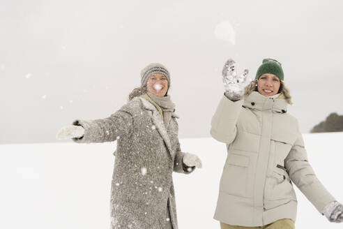Glückliche Frauen beim Schneeballwerfen im Winter - SEAF01847