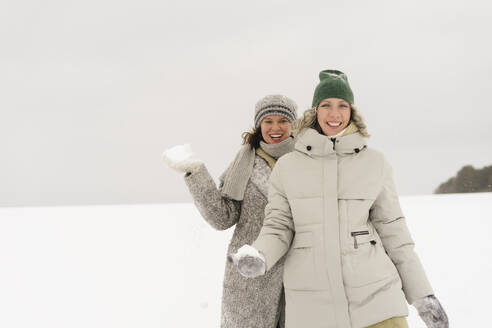 Glückliche Frauen, die im Winter mit einem Schneeball spazieren gehen - SEAF01848