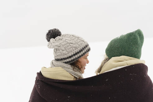 Glückliche Freunde in Schal eingewickelt mit Blick auf den Schnee - SEAF01856