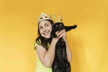 Glückliches Mädchen und Katze mit Krone vor gelbem Hintergrund - OSF01487