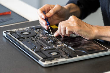 Man repairing laptop with screwdriver - NDF01551