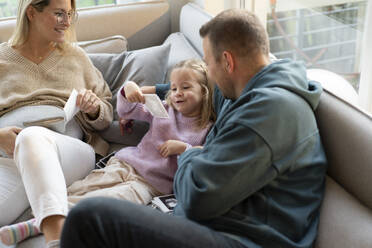 Parents showing ultrasound scan photos to daughter at home - MOEF04452