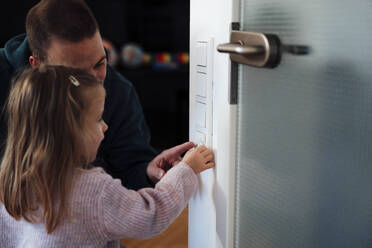 Tochter mit Vater beim Einstellen der Temperatur zu Hause - MOEF04463