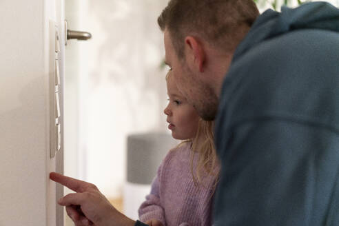 Vater hilft Tochter beim Einstellen der Temperatur am Thermostat zu Hause - MOEF04467