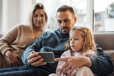 Father sharing mobile phone with daughter at home - MOEF04470