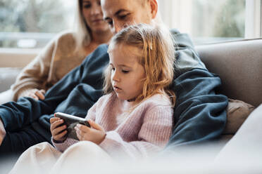 Tochter schaut zu Hause auf das Smartphone der Eltern - MOEF04471