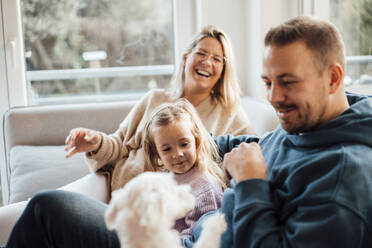 Glückliche Familie spielt mit Hund zu Hause - MOEF04477