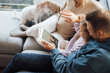 Videoanruf eines Mädchens mit ihrem Großvater über einen Tablet-PC, der bei ihren Eltern zu Hause steht - MOEF04479