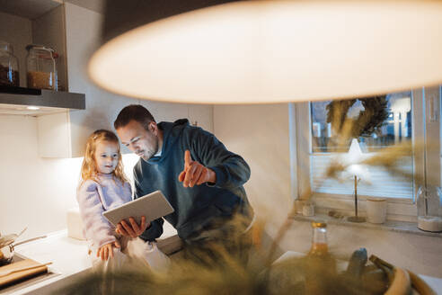 Vater teilt Tablet-PC mit Tochter in Küche - MOEF04485
