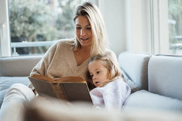 Mutter liest ihrer Tochter zu Hause ein Buch vor - MOEF04511