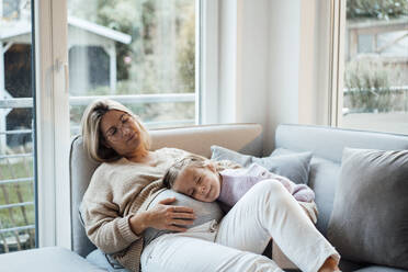 Girl with eyes closed resting head on pregnant woman's belly at home - MOEF04520