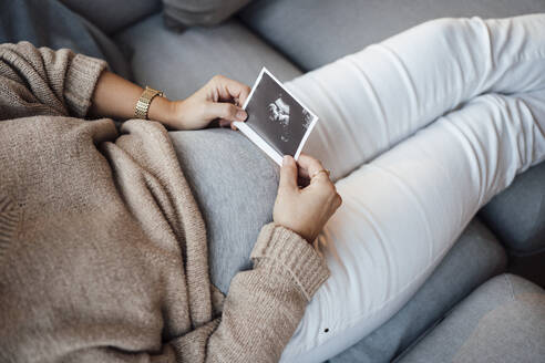 Schwangere Frau hält Ultraschallfoto zu Hause - MOEF04522