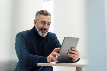 Smiling businessman using tablet PC at desk - JOSEF17937