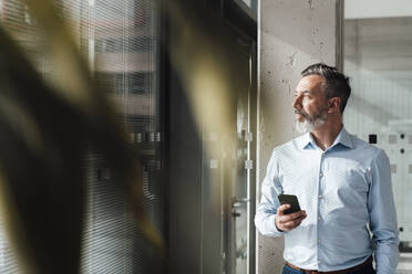 Geschäftsmann stehend mit Smartphone im Büro - JOSEF18003