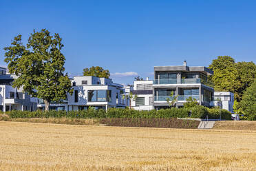 Deutschland, Baden-Württemberg, Ludwigsburg, Feld vor modernen Vorstadthäusern - WDF07294