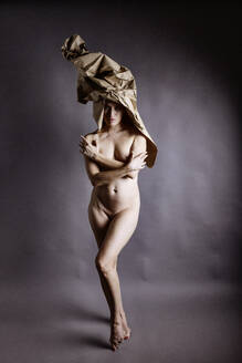 Naked woman wearing paper hat standing on toe - JATF01357