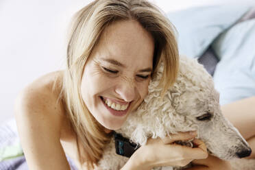 Glückliche Frau umarmt Hund zu Hause - JATF01365