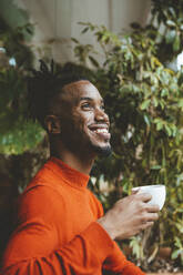 Nachdenklicher glücklicher Mann mit Kaffeetasse sitzend - JOSEF18101