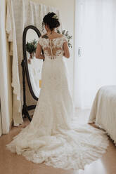 Braut im Hochzeitskleid schaut in den Spiegel - GMLF01331