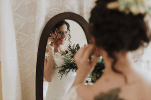 Happy bride looking in mirror on wedding day - GMLF01332