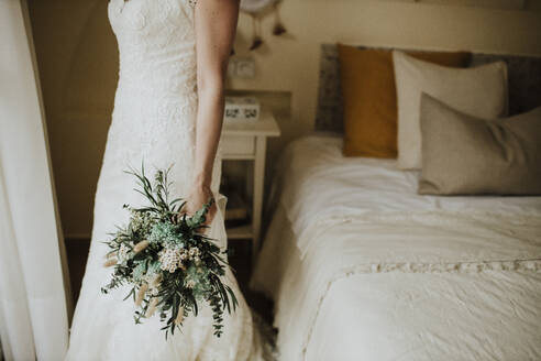 Bride holding bouquet of flowers in bedroom - GMLF01333