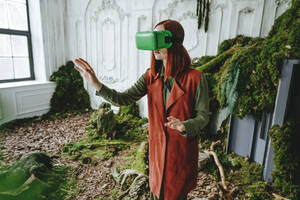 Rothaarige Frau, die einen Virtual-Reality-Simulator trägt, gestikuliert und steht an einem verlassenen Ort - YTF00674