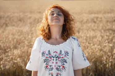 Smiling redhead woman standing in field - AAZF00239