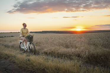 Woman riding bicycle at sunset - AAZF00246