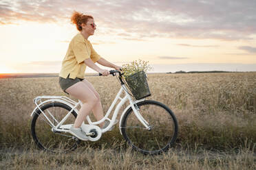 Frau fährt Fahrrad in einem Feld - AAZF00249