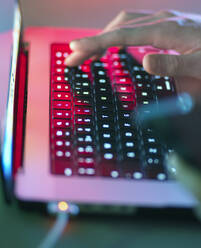 Man typing on illuminated keyboard at office - ABRF01069