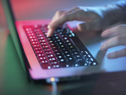 Hacker arbeitet an beleuchtetem Laptop im Büro - ABRF01070