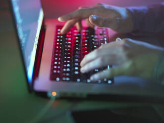 Hacker tippt auf beleuchteter Laptop-Tastatur im Büro - ABRF01071