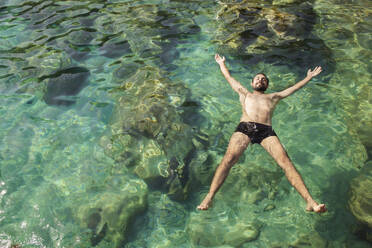 Junger Mann schwimmt auf dem Wasser im Meer - PCLF00304