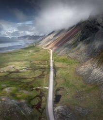 Luftaufnahme einer Straße entlang der Küstenlinie in Stokksnes mit dem Berg Vesturhorn an der Seite, Austurland, Island. - AAEF17720