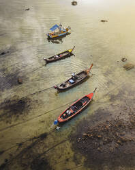 Luftaufnahme einiger Boote, die im Schlamm entlang der Küste bei Sonnenaufgang in Phuket, Thailand, angedockt sind. - AAEF17848