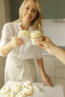 Glückliche Frau, die mit einem Freund auf Muffins anstößt - VIVF00463