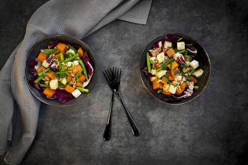 Two bowls of ready-to-eat vegetarian salad with sweet potato, celery, radicchio, green beans, croutons, walnuts and parsley - LVF09297